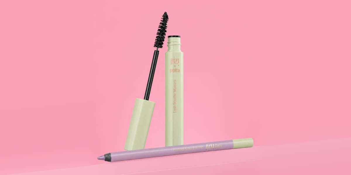 A cosmetic makeup set featuring a light green mascara tube with the wand removed and standing beside it, and a lavender lip liner pencil lying in front, all set against a solid pink background. View 2
