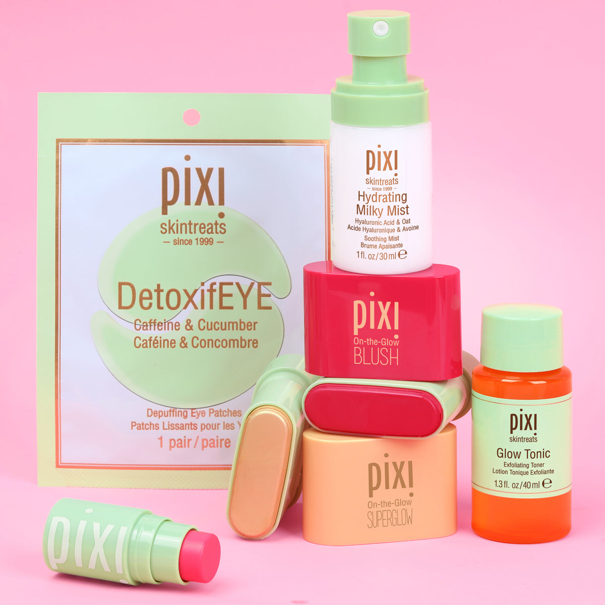 Pixi Skintreats skincare set on a pink background, featuring DetoxifEYE eye patches, a Hydrating Milky Mist, On-the-Glow Blush and SuperGlow Petites and others.